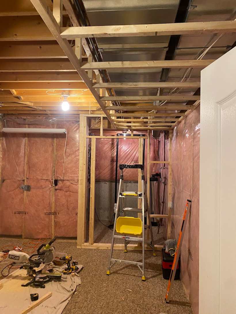 Unfinished basement with bare studs and insulation before Putty Pros finished it