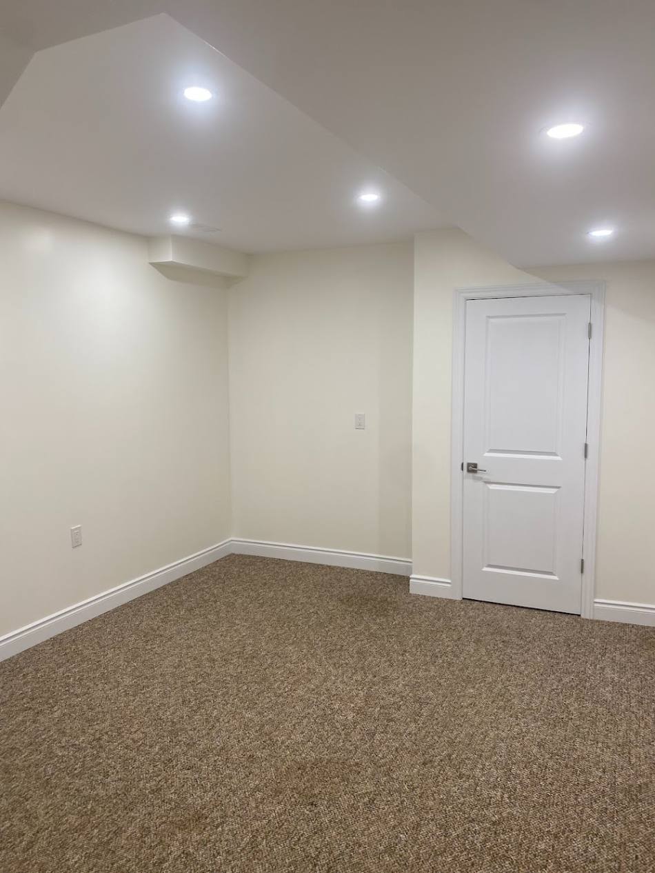 The same basement finished with smooth painted drywall, pot lights, trim and carpet