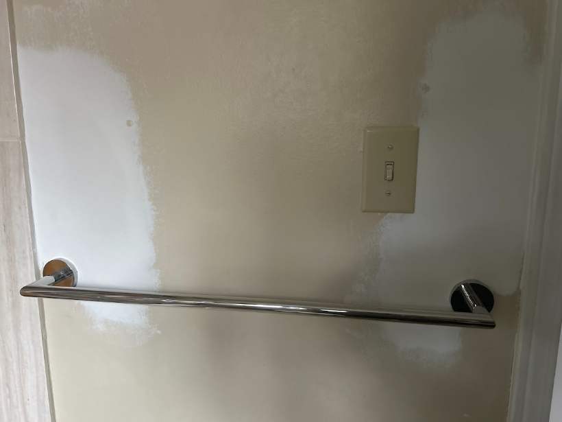 Repaired and repainted drywall with towel bar reinstalled